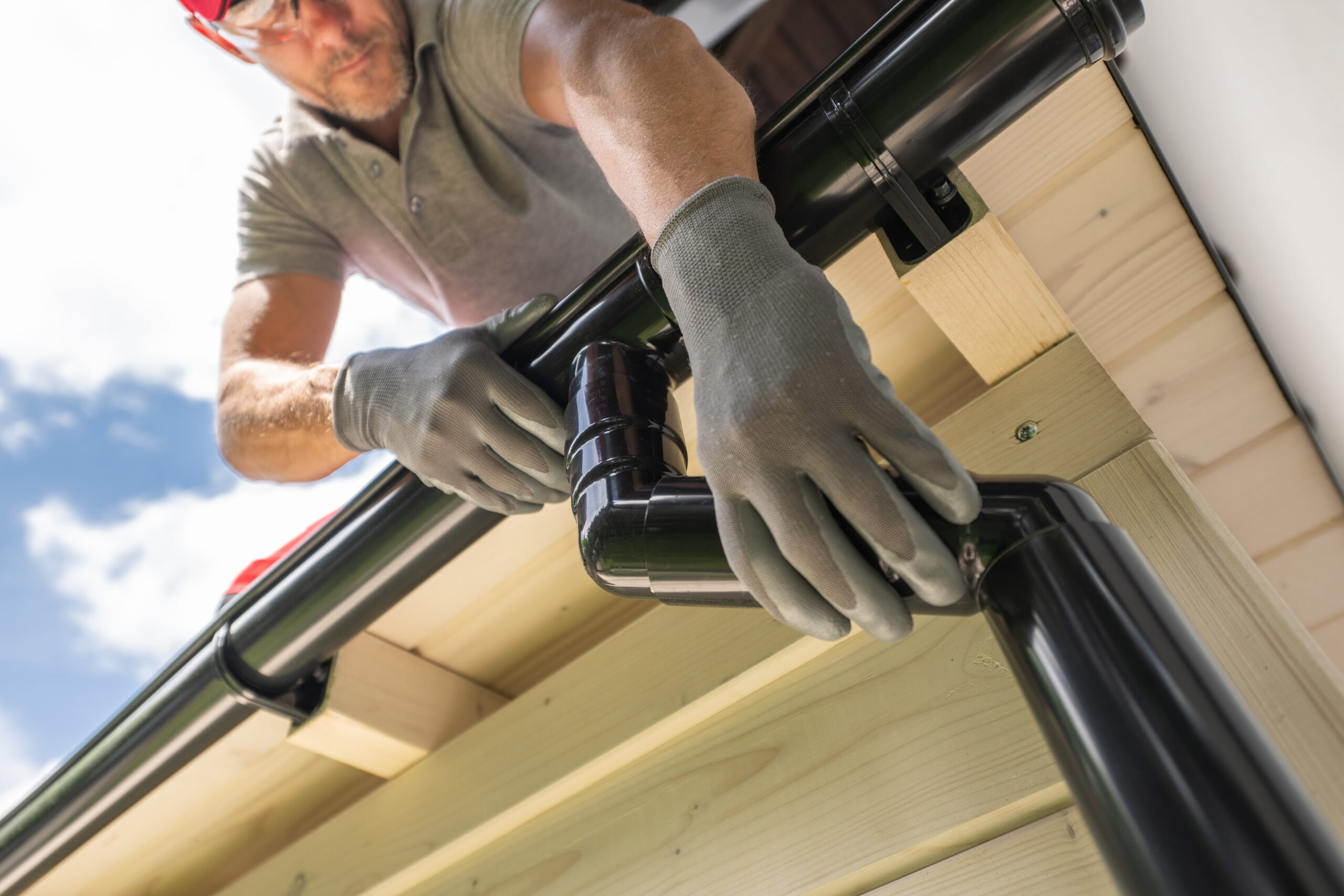 Worker Installing Gutter System on Roof.