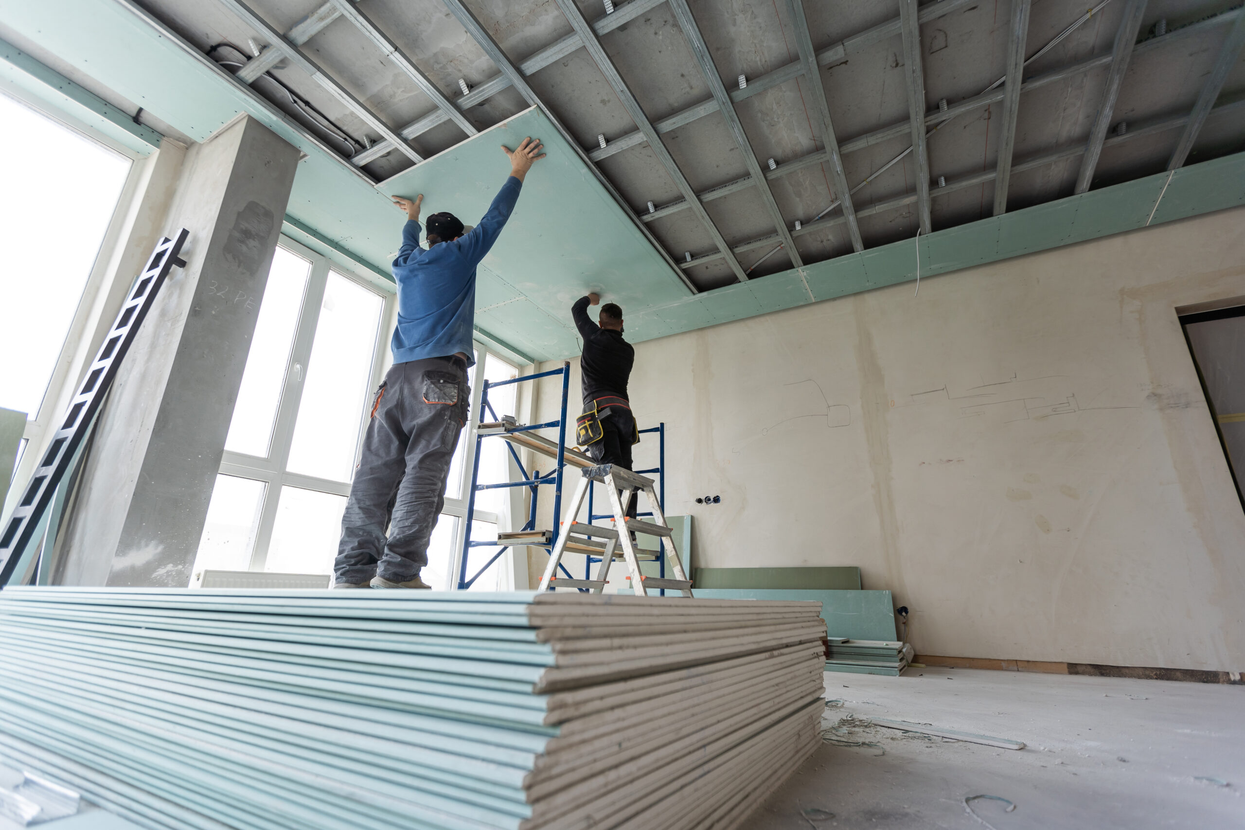 A construction worker is installing ceiling work.